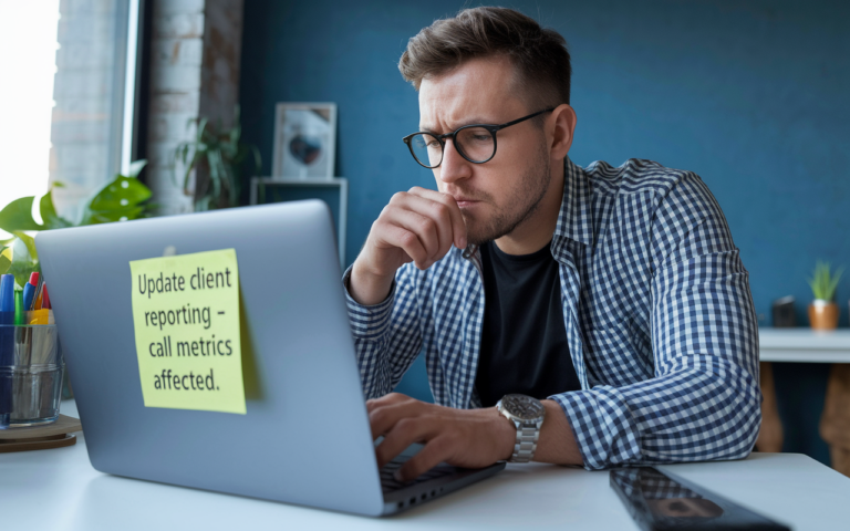 Man focused on laptop with sticky note reminder.
